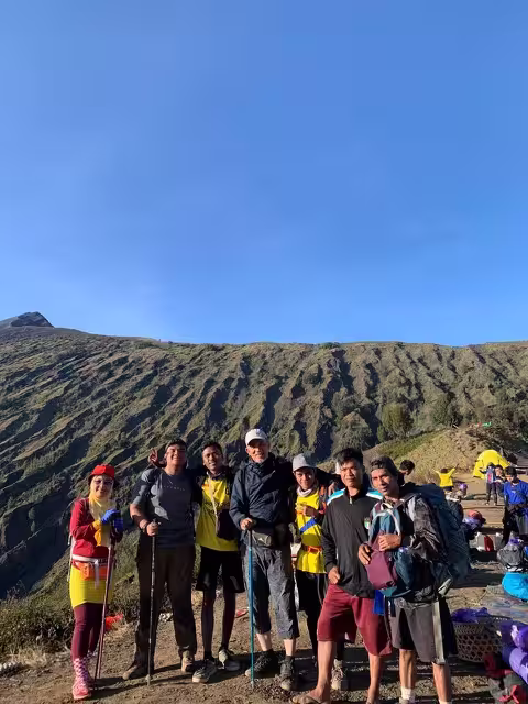 A group of international trekkers and local guides posing together at a Rinjani campsite with go2rinjani