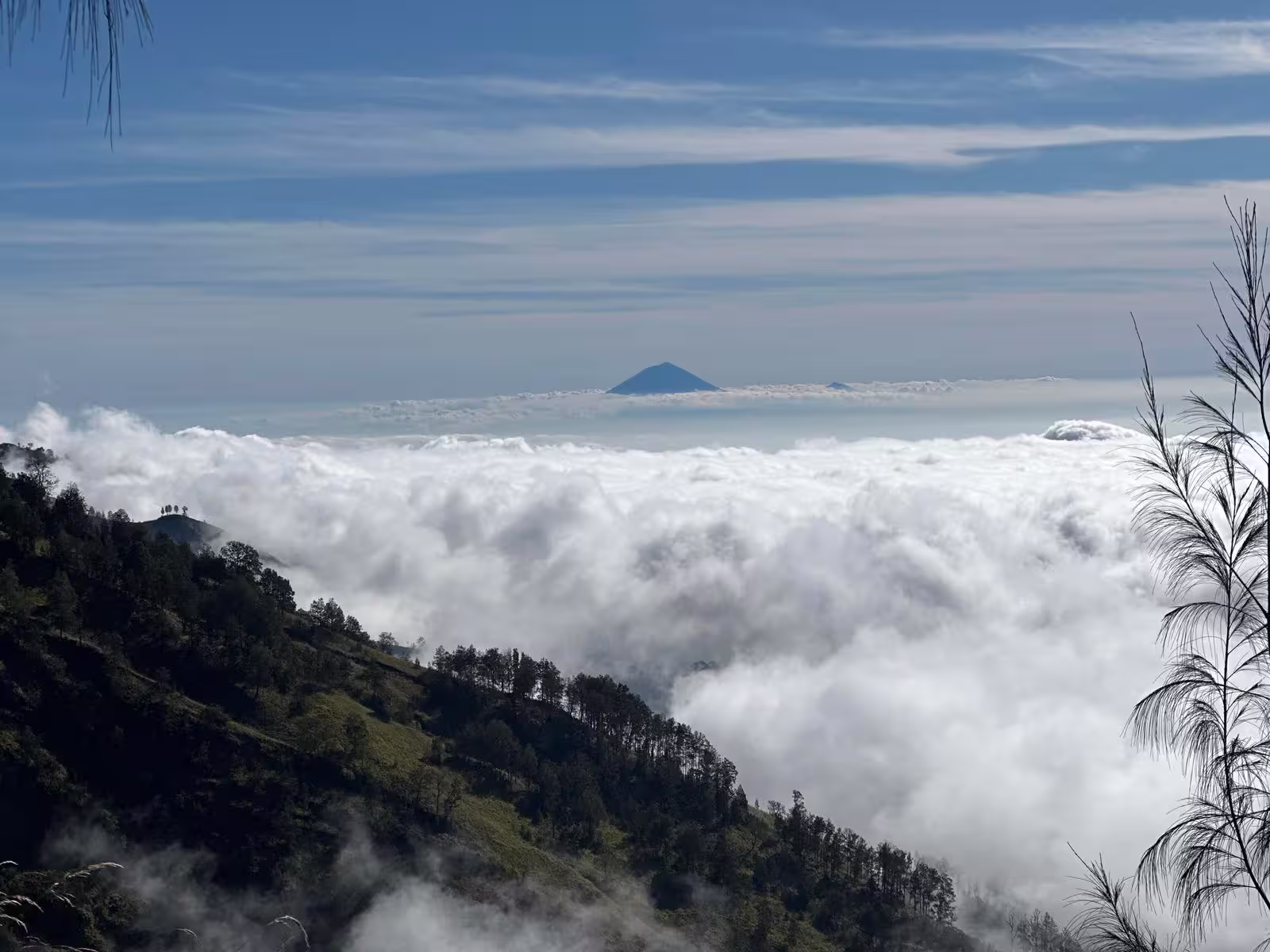 Mount Agung peak rising above a sea of clouds as seen from the Mount Stampol trek near Rinjani