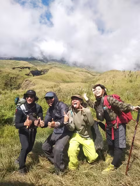 Hikers walking through the vast golden savannah of the Sembalun trail