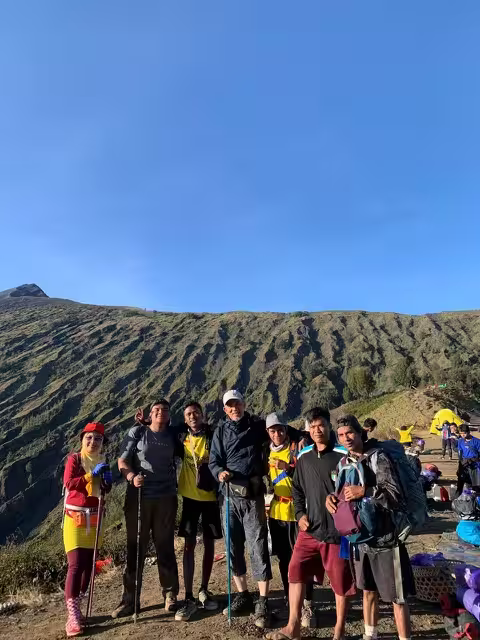 A group of international trekkers and local guides posing together at a Rinjani campsite with go2rinjani