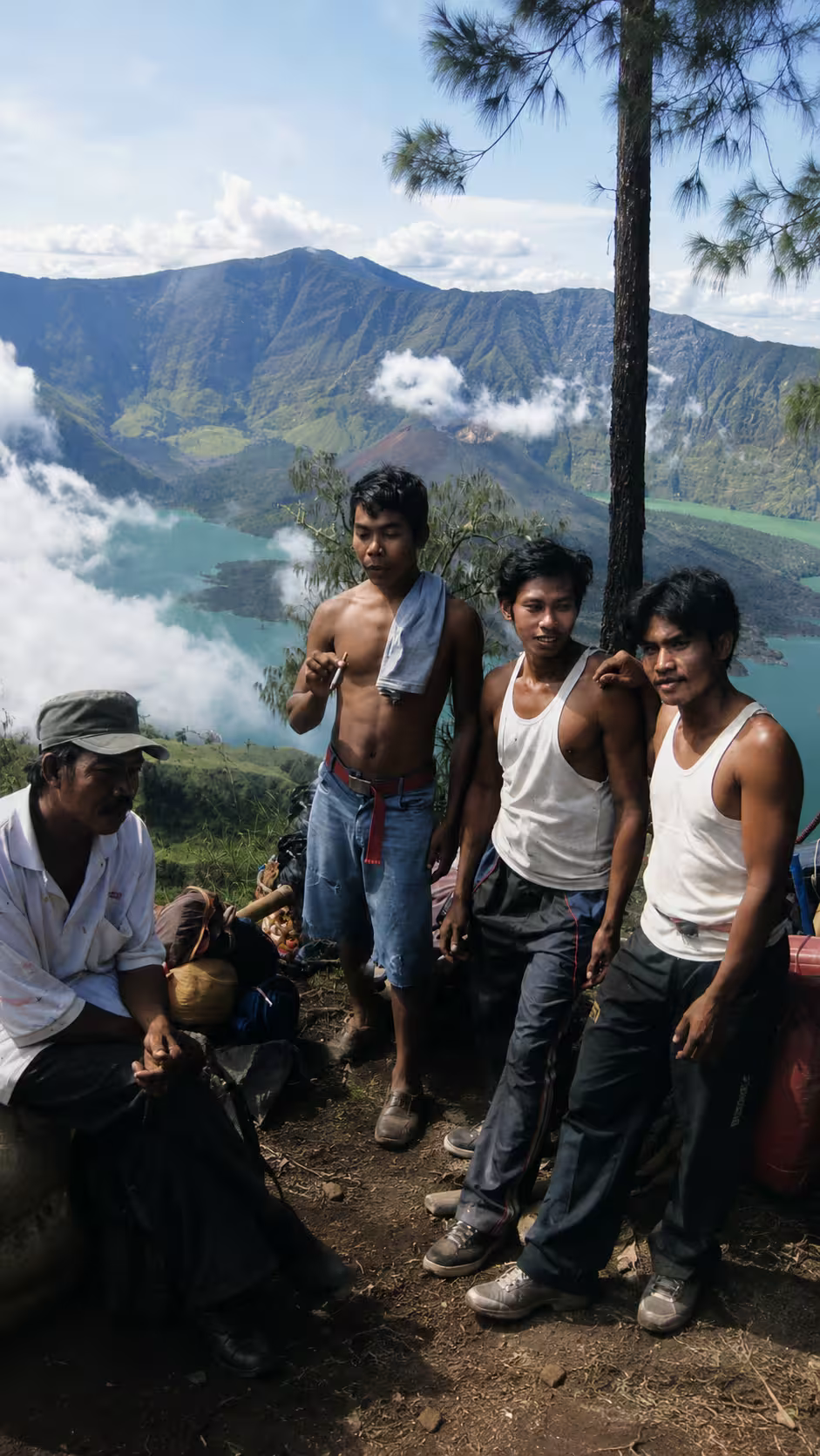 Local Sasak guides and porters resting on the trail overlooking Segara Anak lake during a go2rinjani expedition