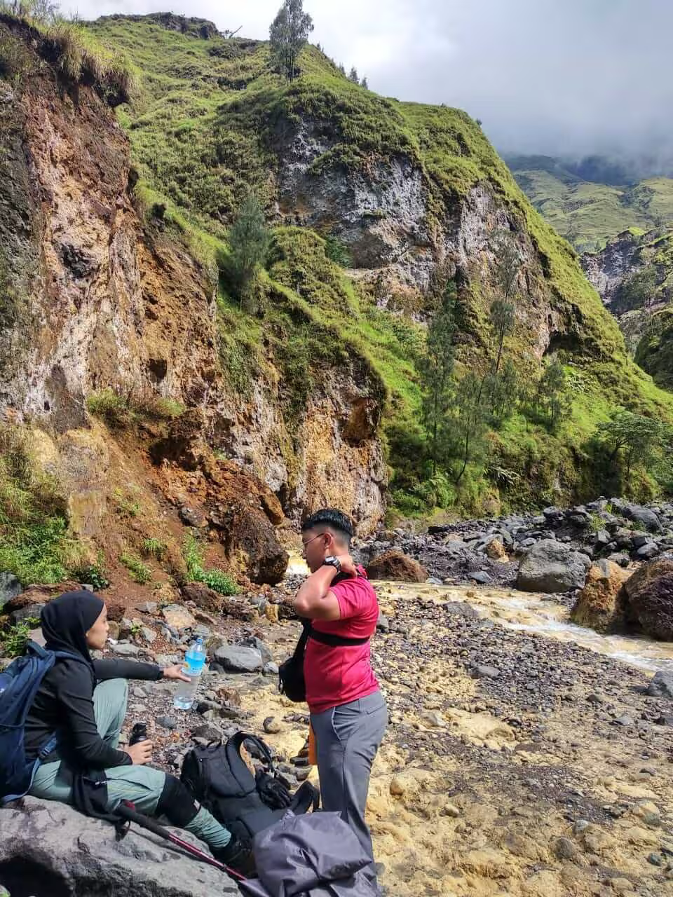 Two trekkers taking a break in the scenic Torean valley riverbed during a go2rinjani trek
