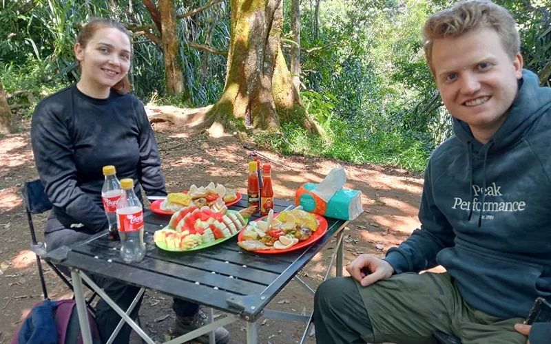 A man and woman having lunch at a table, resting during their 3-day trek on the Senaru route to Mount Rinjani A man and woman having lunch at a table, resting during their 3-day trek on the Senaru route to Mount Rinjani