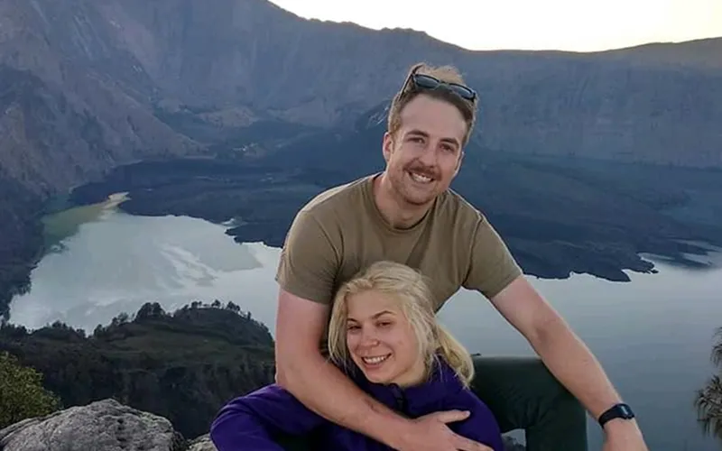 A man and woman relax on a mountain top, enjoying the view after their Mount Rinjani trek via the Senaru route A man and woman relax on a mountain top, enjoying the view after their Mount Rinjani trek via the Senaru route