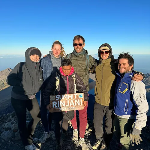 A group of hikers celebrating at the summit of Mount Rinjani after a successful climb via the Sembalun route A group of hikers celebrating at the summit of Mount Rinjani after a successful climb via the Sembalun route