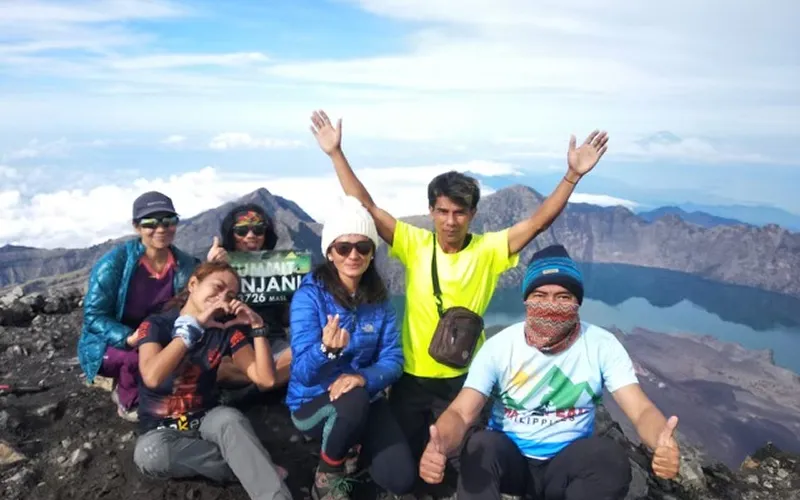 A group of hikers smiling for a photo at the summit of Mount Rinjani after a 4-day trek via the Senaru route A group of hikers smiling for a photo at the summit of Mount Rinjani after a 4-day trek via the Senaru route