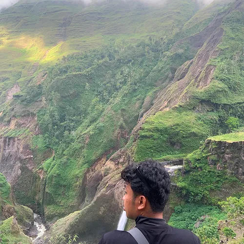 A man stands on a cliff, gazing at a vast valley during a Mount Rinjani hike from Torean A man stands on a cliff, gazing at a vast valley during a Mount Rinjani hike from Torean