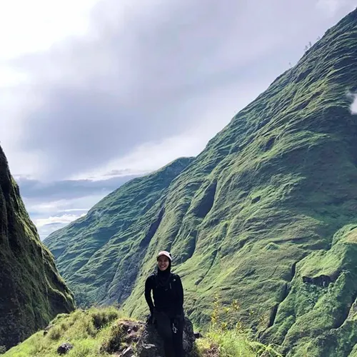 A person sitting on a rock, admiring the towering Mount Rinjani during a 3-day hike from Torean A person sitting on a rock, admiring the towering Mount Rinjani during a 3-day hike from Torean