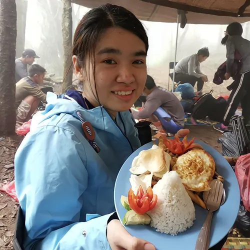 A woman enjoying a plate of food while on the Mount Rinjani hike at Crater Rim Senaru A woman enjoying a plate of food while on the Mount Rinjani hike at Crater Rim Senaru