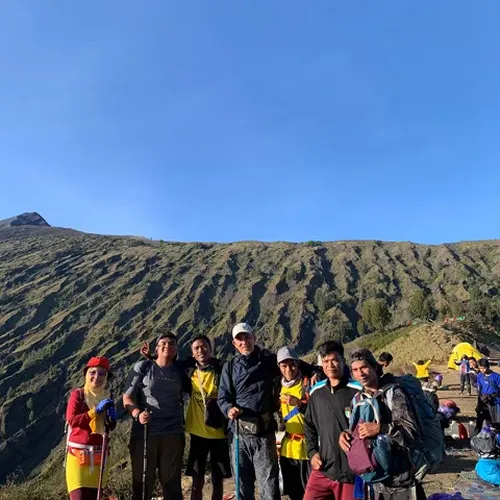 Four hikers on a mountain summit, backpacks on, enjoying the view after a 4-day trek on the Senaru route to Mount Rinjani Four hikers on a mountain summit, backpacks on, enjoying the view after a 4-day trek on the Senaru route to Mount Rinjani