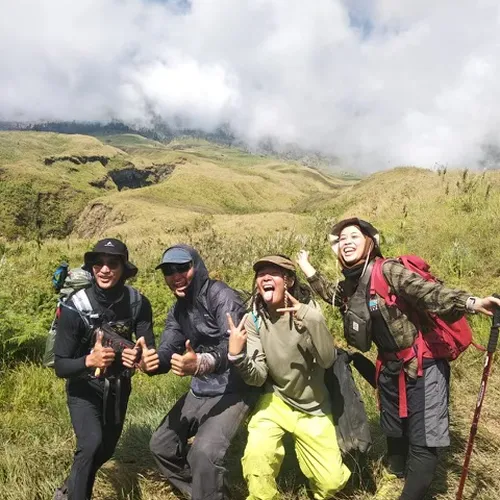 Four hikers smiling together on a mountain summit after a 4-day trek on the Senaru route at Mount Rinjani Four hikers smiling together on a mountain summit after a 4-day trek on the Senaru route at Mount Rinjani