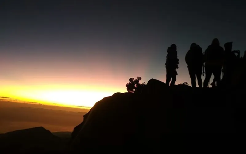 Group of hikers standing on Mount Rinjani summit at sunset, overlooking the stunning landscape from the Sembalun route Group of hikers standing on Mount Rinjani summit at sunset, overlooking the stunning landscape from the Sembalun route