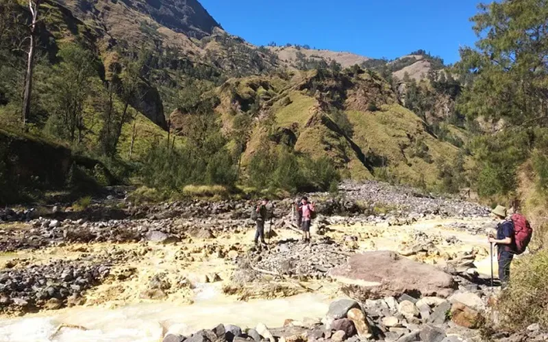 Hikers walking on a rocky mountain path during a 3-day trek to Mount Rinjani's summit Hikers walking on a rocky mountain path during a 3-day trek to Mount Rinjani's summit