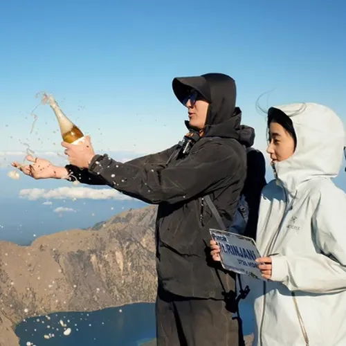 On Mount Rinjani, a man and woman pop champagne, celebrating their successful summit hike via the Sembalun route On Mount Rinjani, a man and woman pop champagne, celebrating their successful summit hike via the Sembalun route