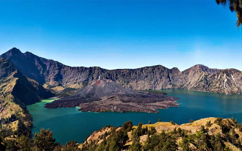 Panoramic view from the top of Mount Rinjani, showcasing lush landscapes and the crater rim of Senaru below Panoramic view from the top of Mount Rinjani, showcasing lush landscapes and the crater rim of Senaru below