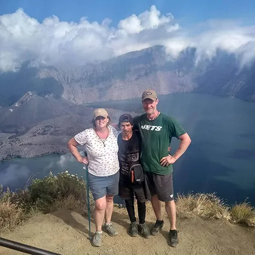 Three adventurers overlook a tranquil lake from the Crater Rim Senaru on their Mount Rinjani trek Three adventurers overlook a tranquil lake from the Crater Rim Senaru on their Mount Rinjani trek