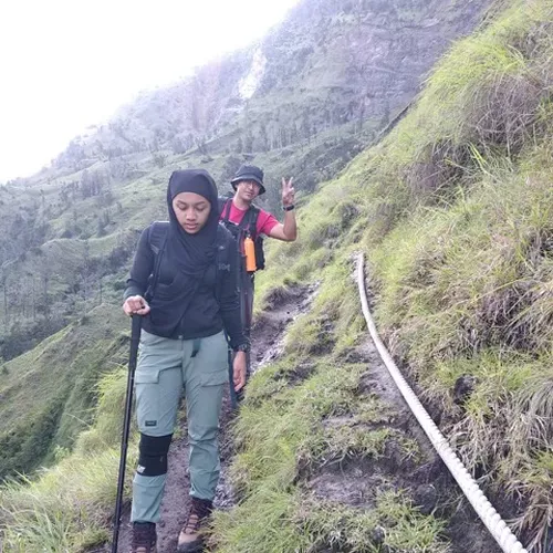 Two individuals trek up a mountain with poles, exploring the Torean route on Mount Rinjani Two individuals trek up a mountain with poles, exploring the Torean route on Mount Rinjani