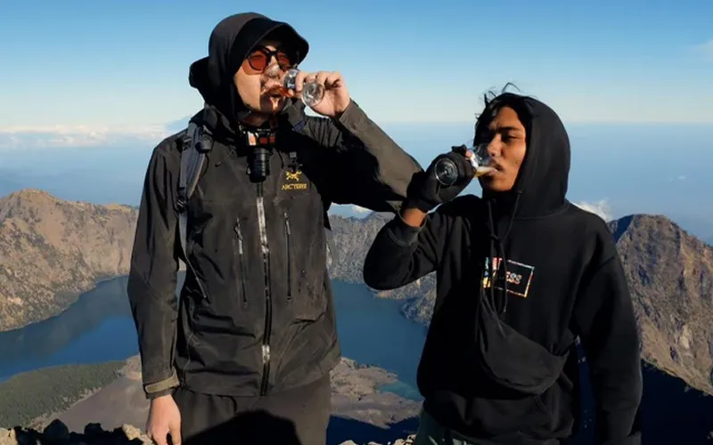 Two men enjoying water at the summit of Mount Rinjani after a hike via the Sembalun route Two men enjoying water at the summit of Mount Rinjani after a hike via the Sembalun route