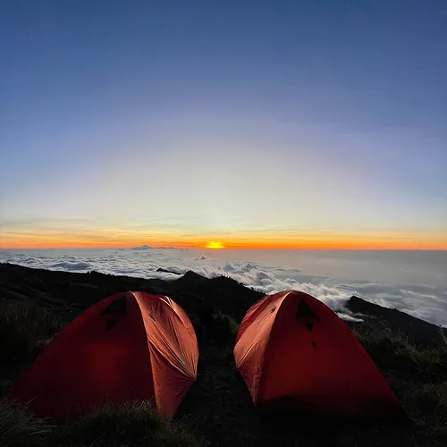 Two tents on a mountain peak at sunset, capturing a serene moment during a Mount Rinjani hike Two tents on a mountain peak at sunset, capturing a serene moment during a Mount Rinjani hike