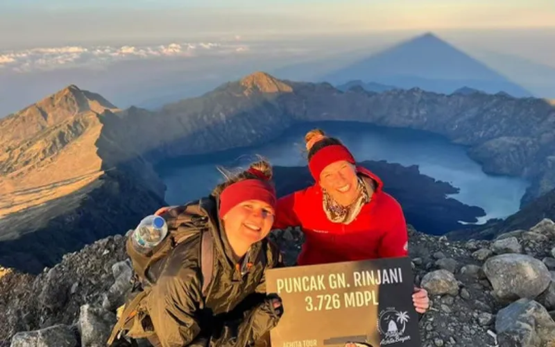 Two women smiling for a photo at the summit of Mount Rinjani after a 4-day hike via the Senaru route Two women smiling for a photo at the summit of Mount Rinjani after a 4-day hike via the Senaru route