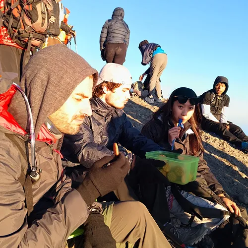 A diverse group of individuals relaxing on a hill, part of a 3-day trek on the Sembalun route of Mount Rinjani A diverse group of individuals relaxing on a hill, part of a 3-day trek on the Sembalun route of Mount Rinjani