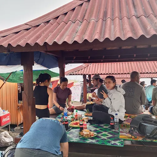 A group of hikers enjoying lunch at a table during their Mount Rinjani trek on the Sembalun route, at Pos 3 A group of hikers enjoying lunch at a table during their Mount Rinjani trek on the Sembalun route, at Pos 3