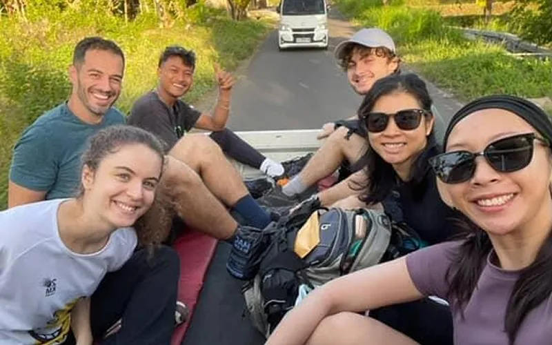 A group of people relaxing on a truck's back, preparing for their summit hike of Mount Rinjani along the Sembalun route A group of people relaxing on a truck's back, preparing for their summit hike of Mount Rinjani along the Sembalun route