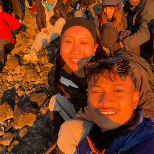 A group of people smiles for a selfie on Mount Rinjani's summit, enjoying the sunrise after a 3-day trek on the Sembalun route A group of people smiles for a selfie on Mount Rinjani's summit, enjoying the sunrise after a 3-day trek on the Sembalun route