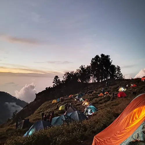 A hillside dotted with tents at sunset, showcasing the tranquil atmosphere of the Sembalun Lawang campsite A hillside dotted with tents at sunset, showcasing the tranquil atmosphere of the Sembalun Lawang campsite