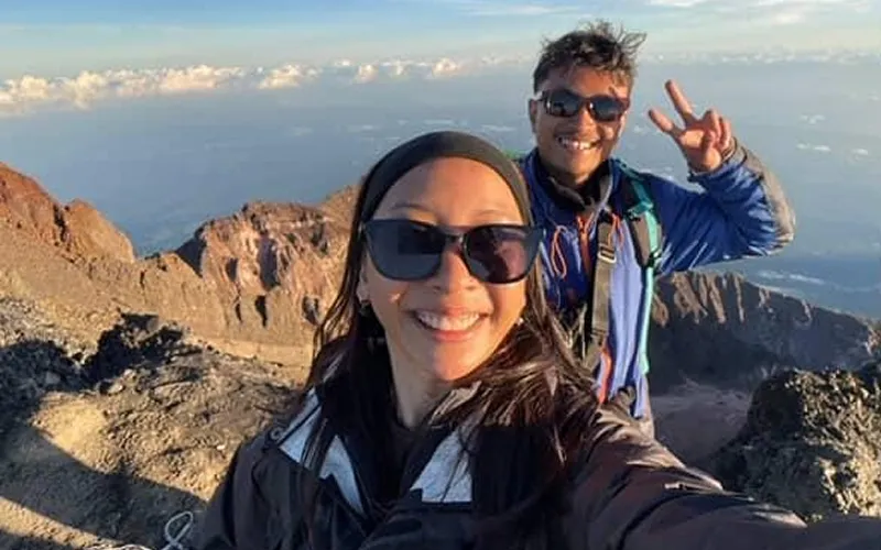 A man and woman take a selfie at the summit of Mount Rinjani, celebrating their successful trek along the Sembalun route A man and woman take a selfie at the summit of Mount Rinjani, celebrating their successful trek along the Sembalun route